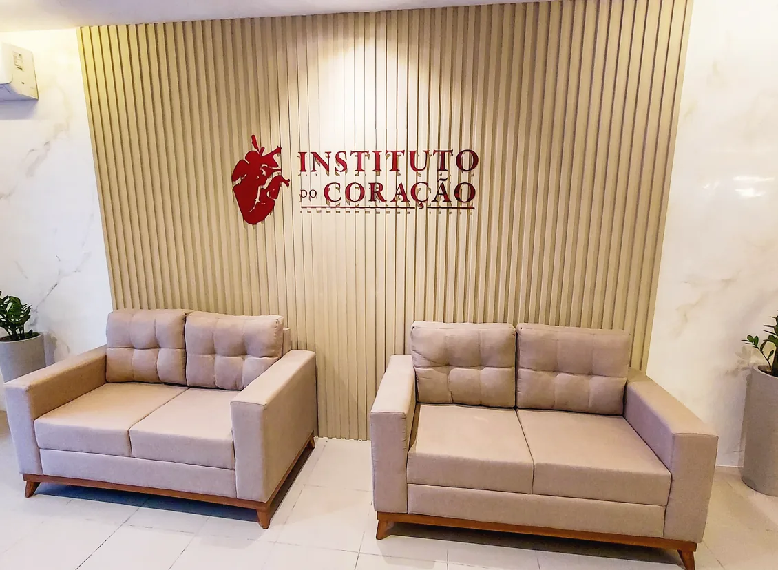 Sala de espera com sofás diante do painel de madeira com o logotipo do Instituto do Coração